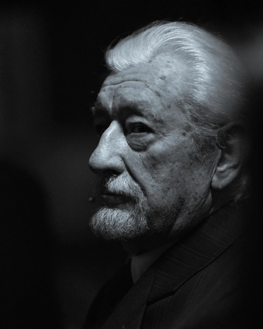 Black-and-white profile portrait of a silver-haired man